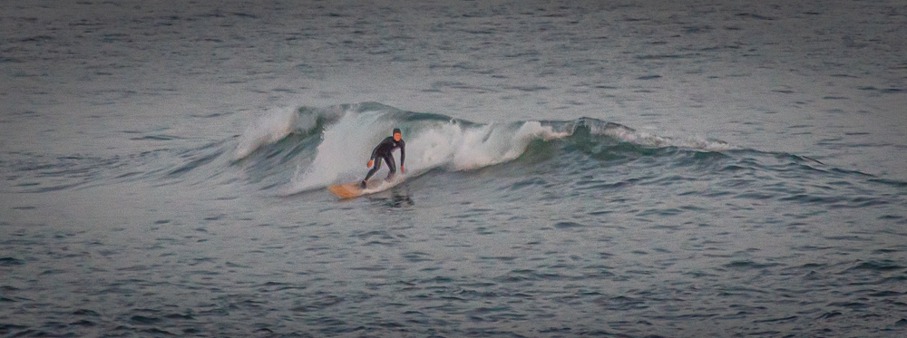 A surfer taking the waves at Spanish Point in County Clare