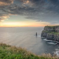 A view of the Cliffs of Moher, taken from the Cliff Walk near Guerin's Path. O'Briens Tower, a sea stack, the Aran Islands and the Connemara Mountains in the distance